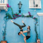 Aaron and Sarah Kat practicing acro in front of a beautiful wall with flowers.